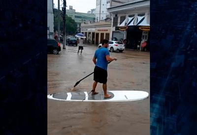 Surfe na enchente: homem usa prancha para se locomover no alagamento Surfe na enchente: homem usa prancha para se locomover no alagamento